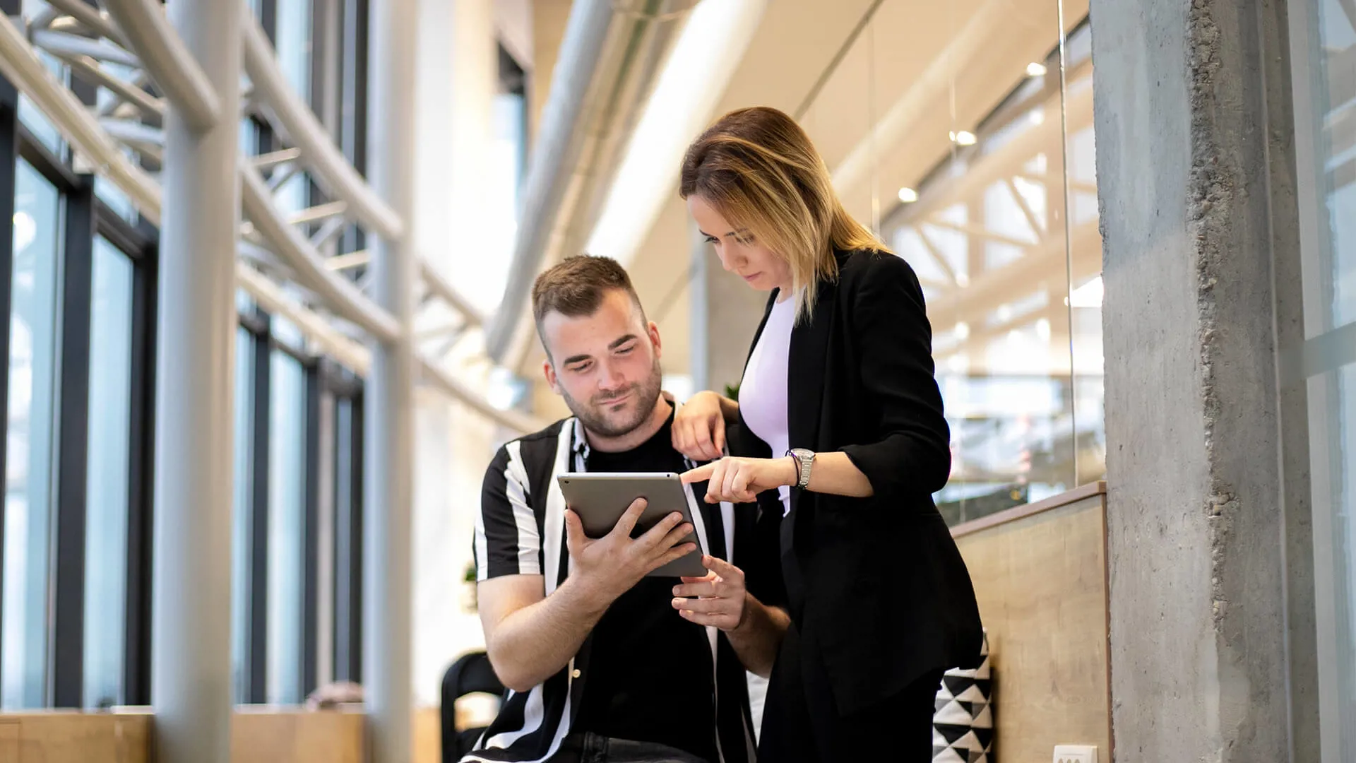 Two colleagues are looking at a tablet and talking